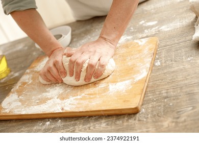 Young man kneading dough on wooden table. Males hands making bread on the kitchen. Baking concept. - Powered by Shutterstock