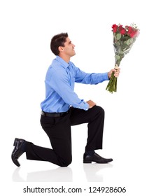 Young Man Knee Down On Floor And Giving Bunch Of Roses Isolated On White