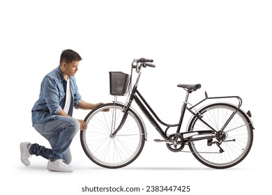 Young man kneeling and checking bicycle wheel isolated on white background