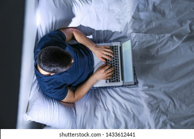 Young Man With Laptop In Bed At Night, Top View