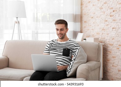 Young Man With Laptop On Sofa In The Room