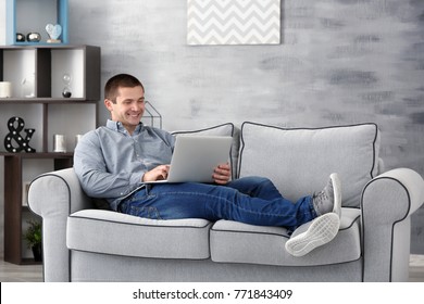 Young Man With Laptop On Sofa At Home