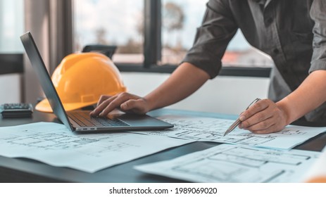 Young man with a laptop plotting a system of building structures in blueprints, Architects or engineers are designing buildings using computers to calculate the physical structure to be correct. - Powered by Shutterstock