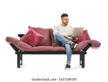 Young Man With Laptop Sitting On Sofa Against White Background