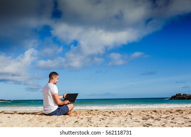 Young Man With Laptop Working On The Sand Beach