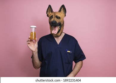 A Young Man In A Latex Dog Head Mask Holding Fish Oil Capsules In A Jar On A Pink Background