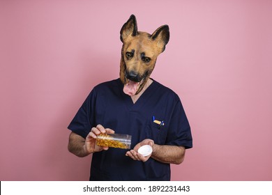 A Young Man In A Latex Dog Head Mask Holding Fish Oil Capsules In A Jar On A Pink Background