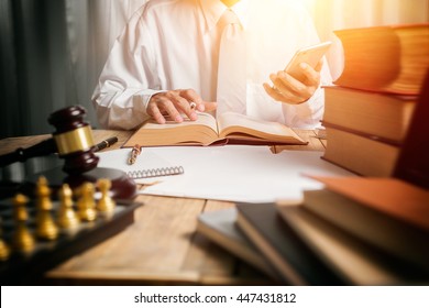 Young Man Lawyer Give Suggestion Mobile Customer And Reading The Lawyer Book For Legislation Issue To Help Afflicted People, Front View Photography With Vintage Picture Style And Sunlight Effect.