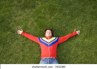 a young man lay down on the grass with plenty copy space