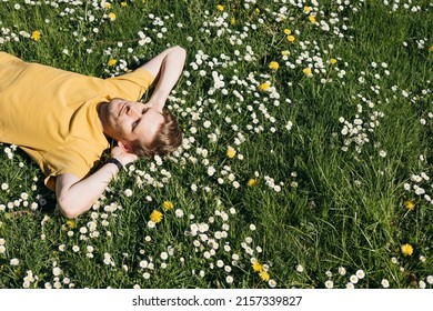 Young man laying in green grass with flowers. People fatigue from work. Summer sleeping and relaxation techniques. Vitamin D sunbathing. Man power nap with eye closed. Rest after work from home - Powered by Shutterstock