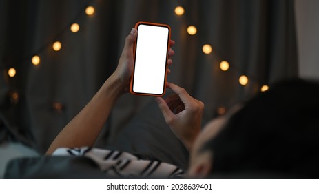 Young Man Laying On His Bed And Using Smart Phone At Night.