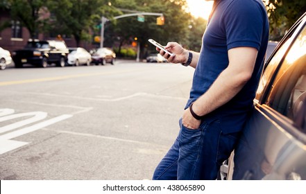 Young Man Leaning On His Car, Using A Smart Phone, Dressed Casually. Flare Light And Vintage Post Processed. Urban Life Style, Technology, Shopping, Roadside Assistance And Job Hunting Concept.