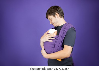 A Young Man Is Learning To Be A Father. Training Of Wearing A Baby On A Doll. Parenting Course