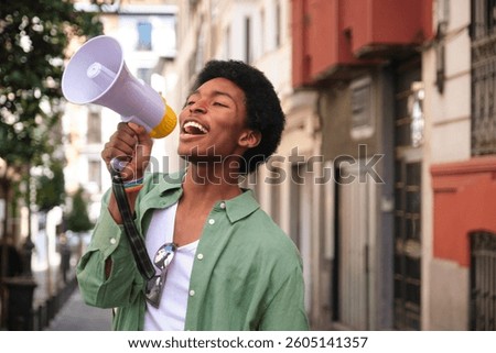Young man with LGBT wristband using megaphone to make his voice heard during a pride parade