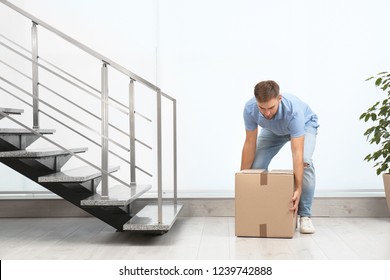 Young Man Lifting Carton Box Indoors. Posture Concept