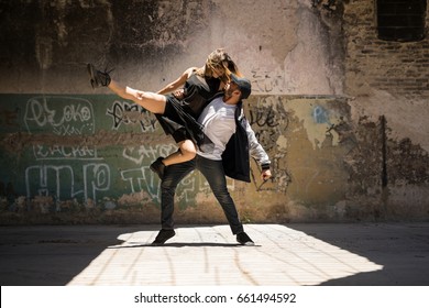 Young man lifting her dancing partner and both looking at each other while performing a dance routine
