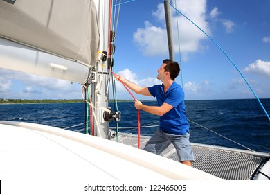 Young Man Lifting The Sail Of Catamaran During Cruising