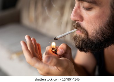 Young Man Lighting A Joint And Smoking Pot. Focus On The Top Of The Joint