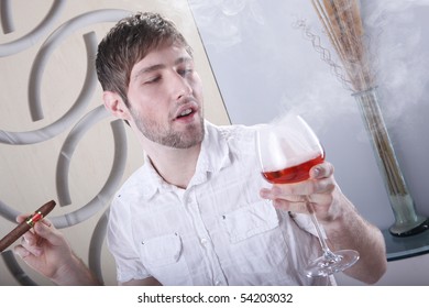 Young Man Lights A Cigar While Sipping Brandy