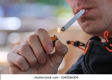 young man lights a cigarette