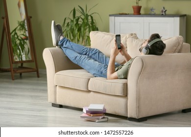Young man listening to audiobook at home