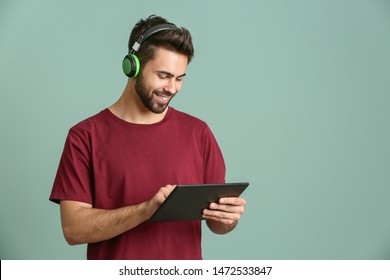 Young Man Listening To Audiobook On Color Background