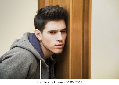 young man placing ear against a door.