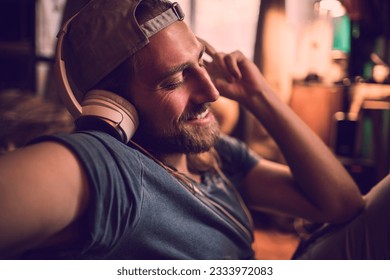 Young man listening to music on his smart phone while sitting in his bedroom - Powered by Shutterstock