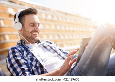 Young Man Listening To Music On A Smart Phone.He Is Listening Music On Smartphone In The City.