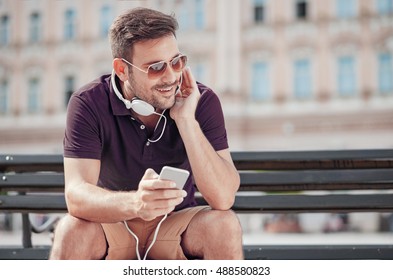 Young man listening to music on a smart phone.He is listening music on smart phone in the city. - Shutterstock ID 488580823