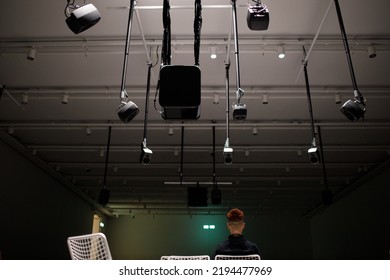 Young man listening to sound music surround installation with many speakers above