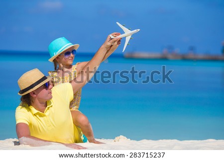 Young man and little girl with miniature of airplane at beach