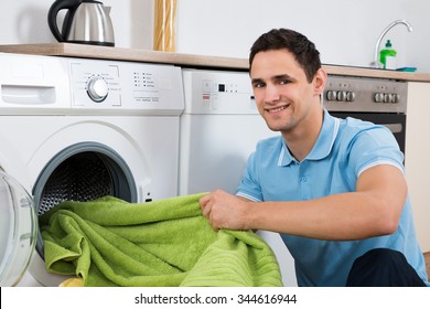 Young man loading towels in washing machine at home - Powered by Shutterstock