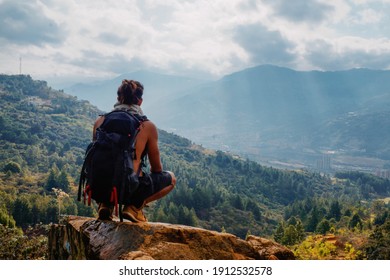 Young man with long hair without shirt and big backpack resting on top and thinking