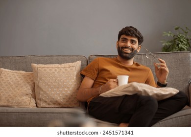 Young man looking away while relaxing on sofa in living room