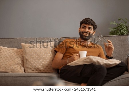 Young man looking away while relaxing on sofa in living room
