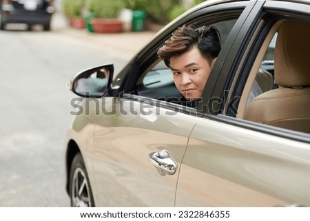 Young man looking back through window when parking in front of house