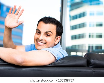 Young Man Looking Behind From Couch And Waving Hello