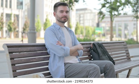 Young Man Looking at Camera while Sitting on Bench