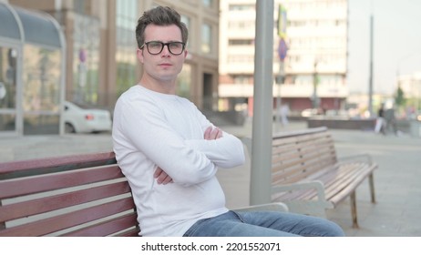 Young Man Looking at Camera while Sitting on Bench