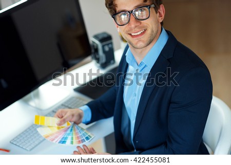 Young man looking to a color paint palette at home office