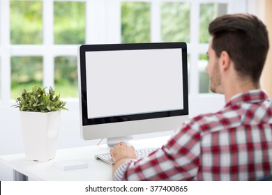 Young Man Looking At Computer Screen At Home Office 