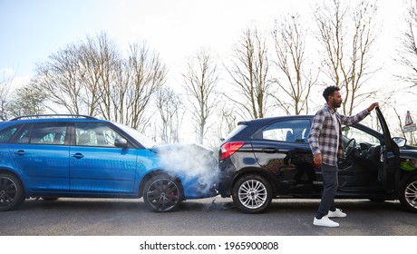 Young Man Looking At Damaged Car Hit From Behind After Traffic Accident