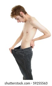 A young man looking down at his old pants when he was fat. Looks like he lost some weight and is now thin! Isolated on white.