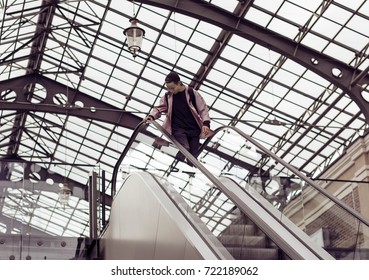 young man looking down standing on escalator steps