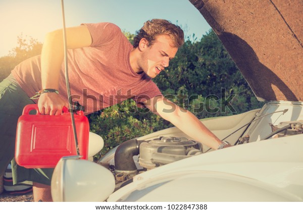 Young man
looking at the engine of a broken
car