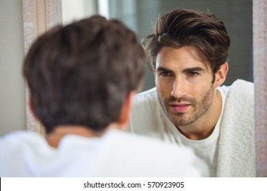 Young Man Looking Himself In Bathroom Mirror