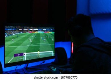 Young man is looking at his phone while playing football game. The room was illuminated with blue light.