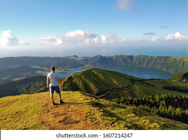 Young man looking into crater of Lagoa Azul and Lagoa Verde (Blue Lake and Green Lake) in Sete Cidades on Sao Miguel, Azore Islands, Portugal. The Azores are known for beautiful nature and landscape.