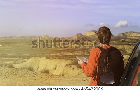 young man looking at map while travel by car in mountains